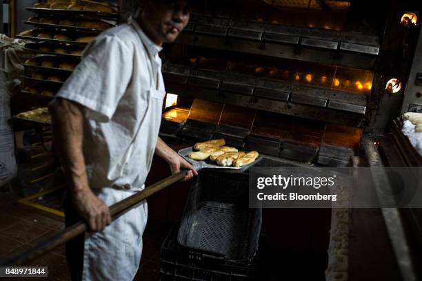 Worker takes canillas, banquette-like bread popular in the country for decades, out of an oven at a bakery in Caracas, Venezuela, on Wednesday, Aug....