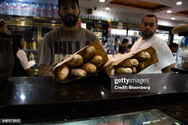 Customer buys bags of canillas, banquette-like bread popular in the country for decades, at a bakery in Caracas, Venezuela, on Wednesday, Aug. 30,...