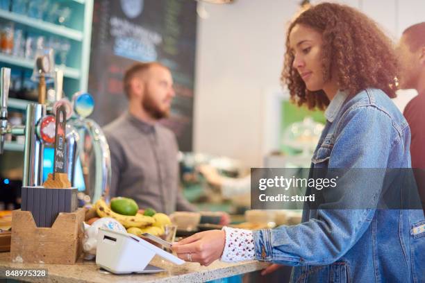 card payment in a cafe - customers pay with contactless cards imagens e fotografias de stock