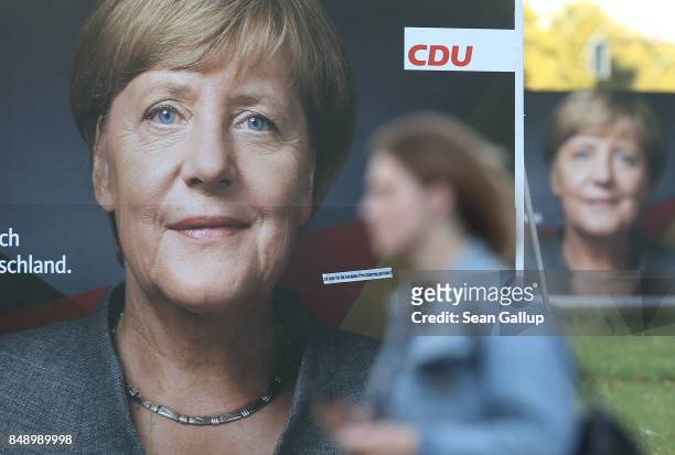 Young woman walks past election campaign billboards that show German Chancellor and Christian Democrat Angela Merkel on September 18, 2017 in Berlin,...