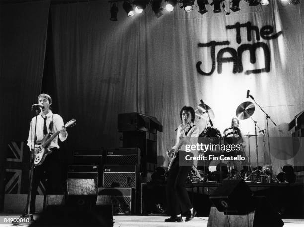 Photo of Paul WELLER and Bruce FOXTON and JAM, Paul Weller, Bruce Foxton, Rick Buckler performing live onstage, with The Jam logo on backdrop behind