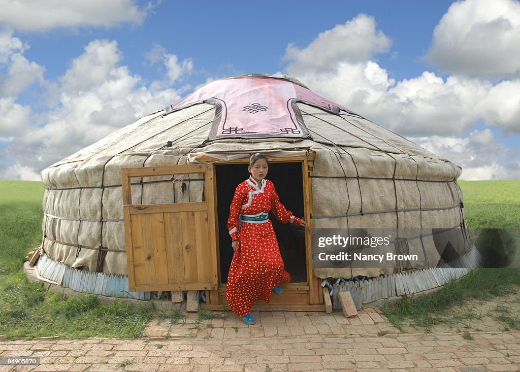 Mongolian Girl stepping out of her Yurt in Inner M