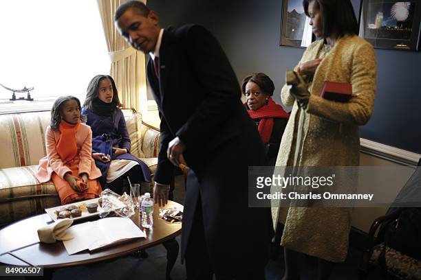 Barack H. Obama, his wife Michelle and daughters Malia and Sasha hold in a small room in the Capital before he is sworn in by Chief Justice John...