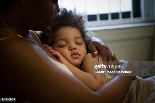 mother holding sleeping son - respite care stock-fotos und bilder
