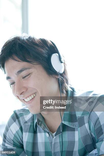 young man wearing head phone, smiling, portrait - hawaii hemd stock-fotos und bilder
