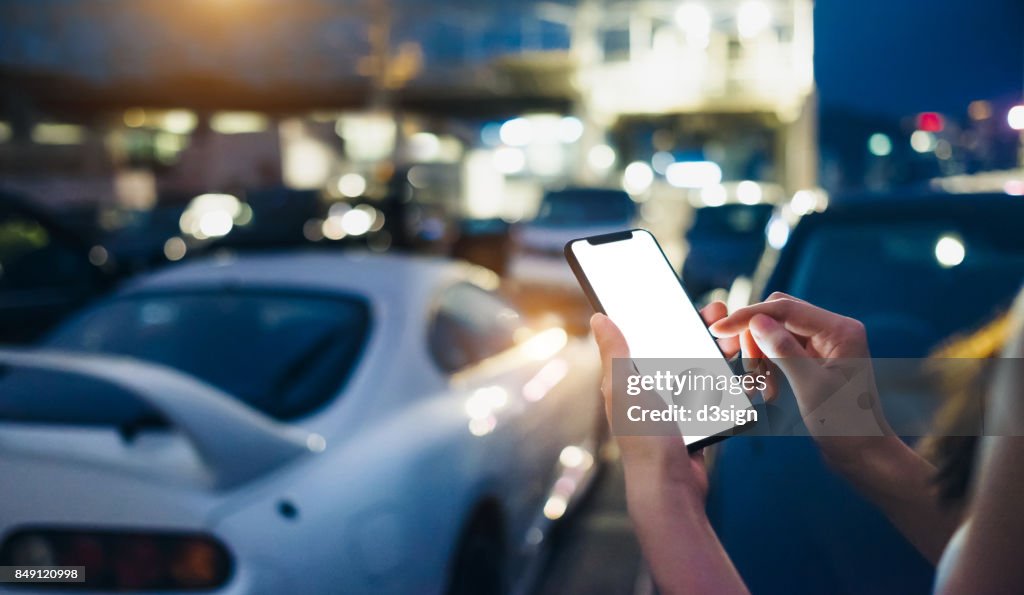 Woman using smartphone while walking to her car in outdoor car park