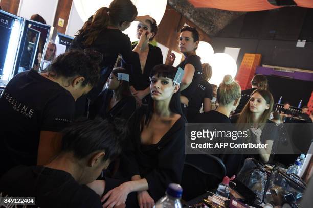 Models are prepared by stylists backstage ahead of the catwalk show by British designer Julien Macdonald during a catwalk show for the Spring/Summer...