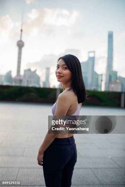 chinese woman walking on the bund by huangpu river with view of the business district,background is the lujiazui finance ceter buildings - the bund foto e immagini stock