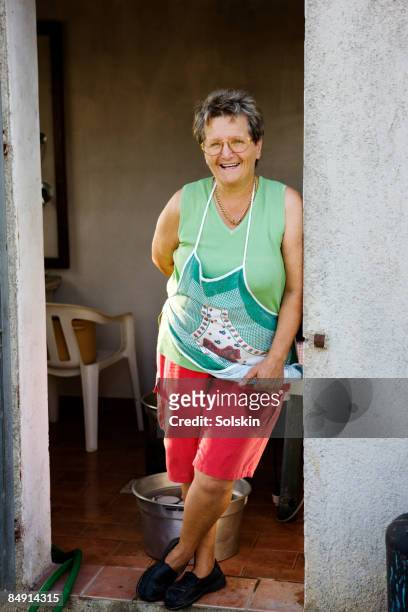 mature woman standing in doorway, smiling - hands behind back stock photos et images de collection