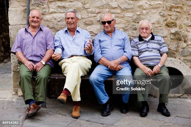 Four elderly men sitting on an outside bench