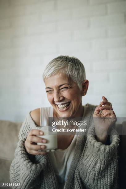 fröhliche reife frau, die spaß beim trinken milch. - milk moustache stock-fotos und bilder