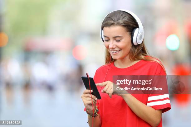 Teen in red listening to music on line on the street
