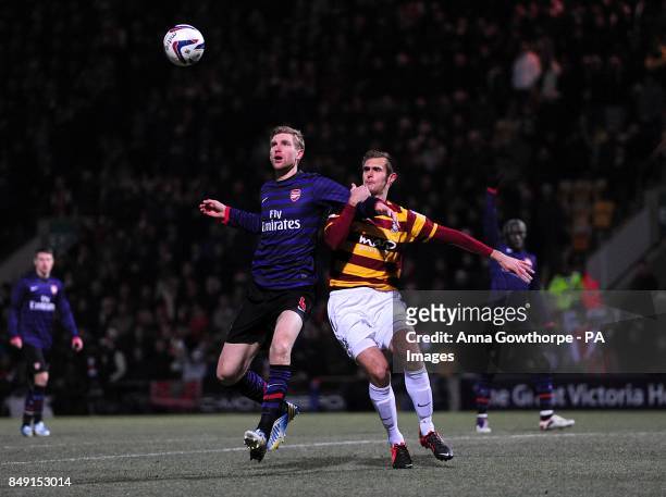 Arsenal's Per Mertesacker and Bradford City's James Hanson battle for the ball