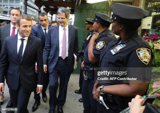 France's President Emmanuel Macron smiles to New York police officers as he walks down 2nd Ave. On his way to the French mission at the United...