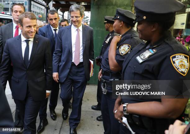 France's President Emmanuel Macron smiles to New York police officers as he walks down 2nd Ave. On his way to the French mission at the United...