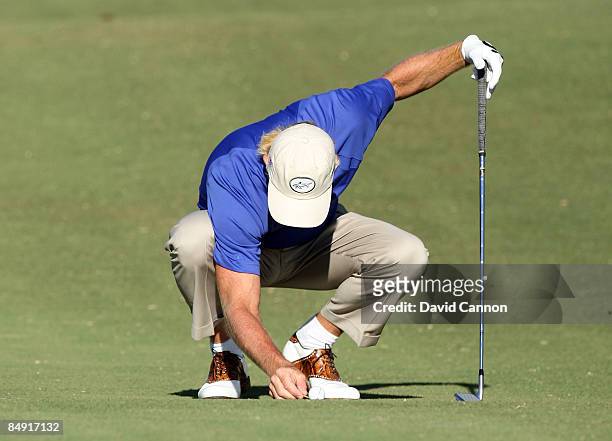 Greg Norman of Australia moves a loose impediment from behind his ball before he hit his second shot at the 14th hole during the first round of the...