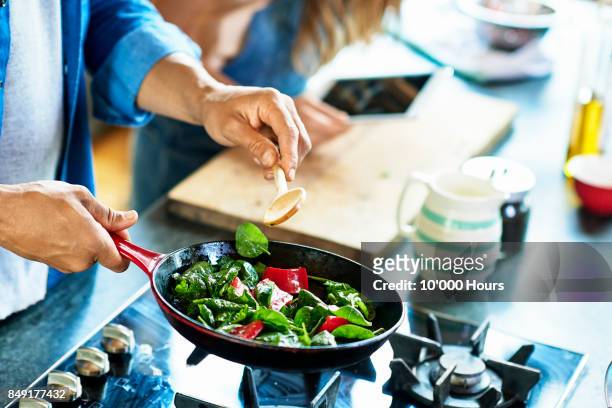 man frying vegetables - espinaca fotografías e imágenes de stock