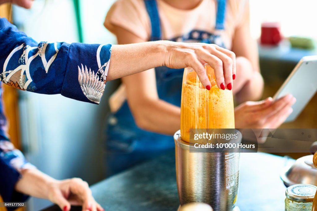 Woman preparing smoothie in blender