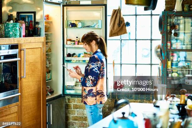 woman using tablet in kitchen - open day 10 stockfoto's en -beelden