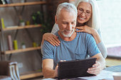 Retired positive man using tablet with his wife