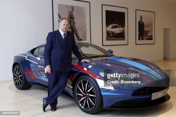 Andy Palmer, chief executive officer of Aston Martin Lagonda Ltd., poses for a photograph with a DB11 sports cars after a Bloomberg Television...
