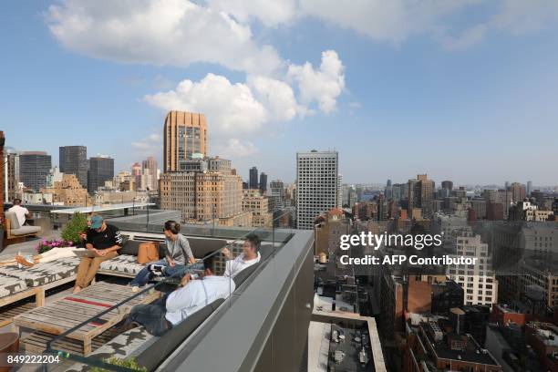 People sit on the rooftop terrace of a hotel in downtown Manhattan on september 17, 2017 in New York city. / AFP PHOTO / ludovic MARIN