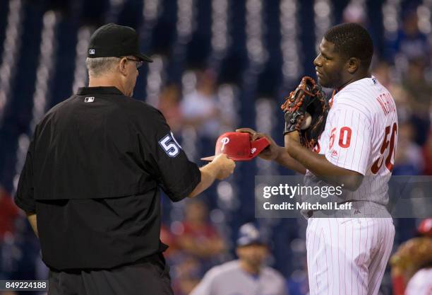 Umpire Paul Emmel inspects the hat of Hector Neris of the Philadelphia Phillies in the top of the ninth inning against the Los Angeles Dodgers at...