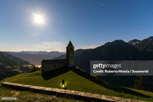 man admires the old church at night, san romerio alp, brusio, switzerland - brusio grisons stock pictures, royalty-free photos & images