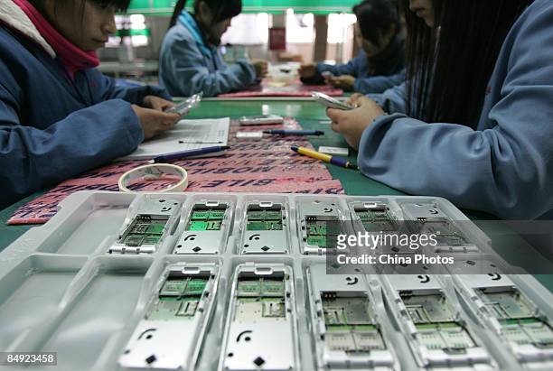 Workers check cell phones on a product line at a factory on February 19, 2009 in Chengdu of Sichuan Province, China. China is facing a difficult...