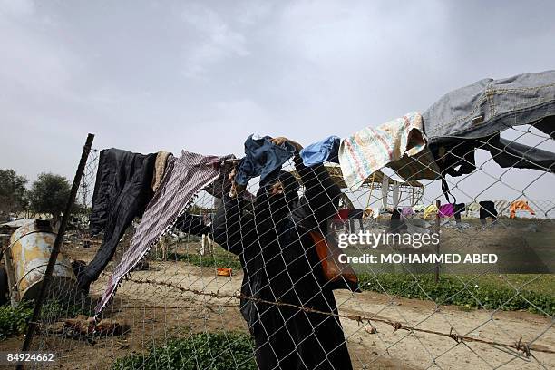 Palestinian woman hangs laundry on a fence outside her destroyed home in Jabalia in the northern Gaza Strip on February 19, 2009. US Democratic...