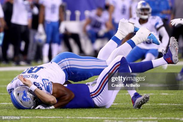 Eli Manning of the New York Giants gets tackled by Cornelius Washington of the Detroit Lions in the fourth quarter during their game at MetLife...