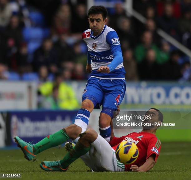Reading's Jem Karacan makes his pass as Swansea's Luke Moore slides on the grass to tackle during the Barclays Premier League match at the Madejski...