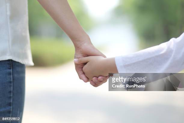 mother walking hand in hand with her daughter - mother daughter holding hands stock pictures, royalty-free photos & images