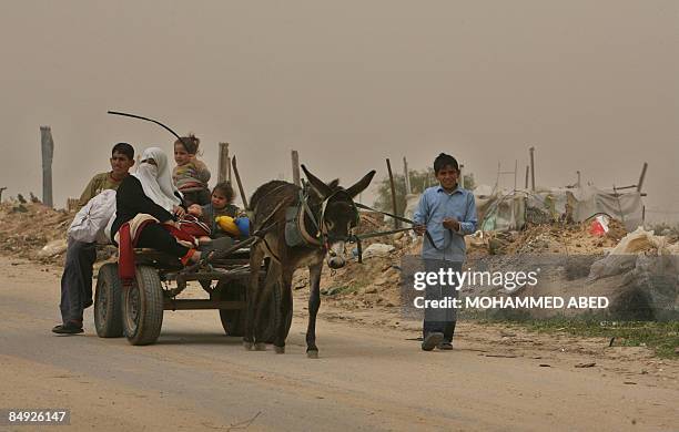 Palestinian family sits on a donkey-pulled cart as they make their way to their house that was destroyed during Israel's offensive in the Jabalia...