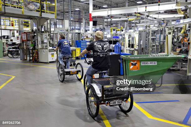 Employees ride trycicles through the Harley-Davidson Inc., powertrain operations facility in Menomonee Falls, Wisconsin, U.S., on Monday, Sept. 18,...