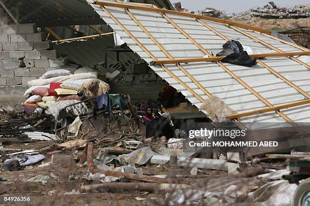 Palestinian woman sits under the roof of her house that was destroyed during Israel's offensive in the Jabalia refugee camp, northern Gaza Strip, on...
