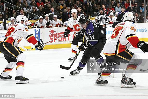 Anze Kopitar of the Los Angeles Kings defends the puck against Robyn Regehr and Adrian Aucoin of the Calgary Flames on February 12, 2009 at Staples...