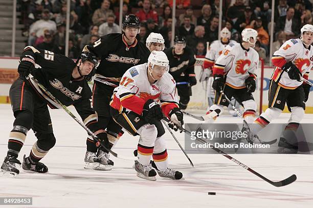 Rene Bourque of the Calgary Flames drives the puck against Chris Pronger and Chris Kunitz of the Anaheim Ducks during the game on February 11, 2009...