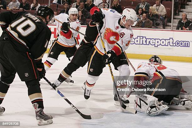 Miikka Kiprusoff and Michael Cammalleri of the Calgary Flames defend in the crease against Corey Perry of the Anaheim Ducks during the game on...