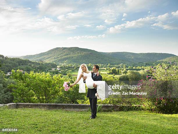 groom carrying bride in garden - well dressed couple isolated stock pictures, royalty-free photos & images