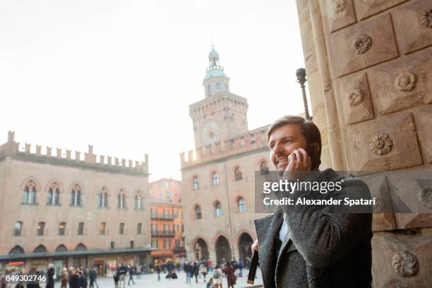 businessman talking on the cell phone at the main square of a european city - main smartphone stockfoto's en -beelden