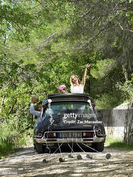 bride and groom waving from wedding car - newlywed fotografías e imágenes de stock