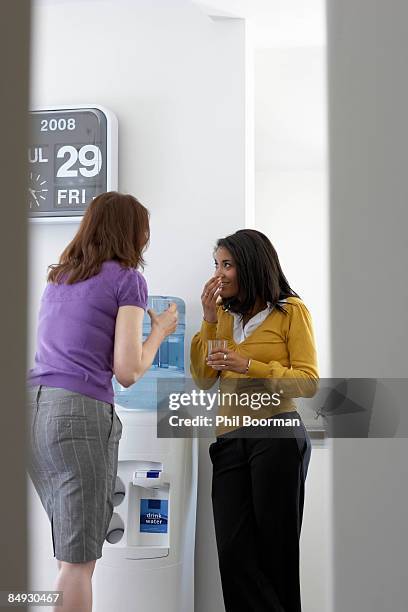 businesswomen gossiping in office - water cooler stockfoto's en -beelden