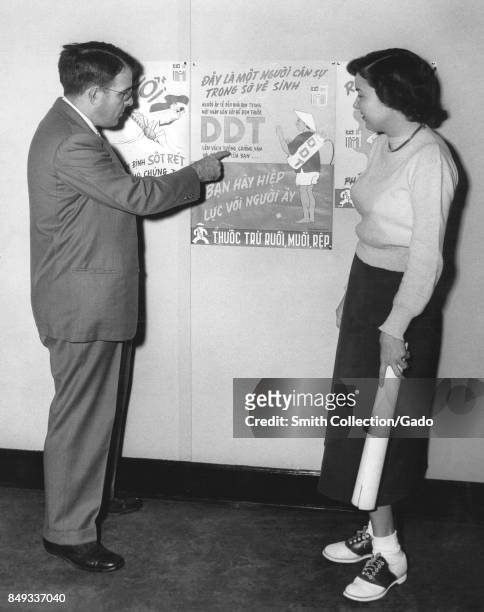 Dr Harry D Pratt, a medical entomologist, shows Ms Martha York a poster about the insecticide DDT part of a Malaria Control Program sponsored by the...