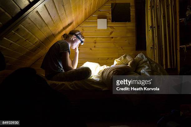a woman reading in bed by headlamp - flashlight stock-fotos und bilder