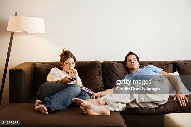 young couple on sofa watching television. - laziness fotografías e imágenes de stock