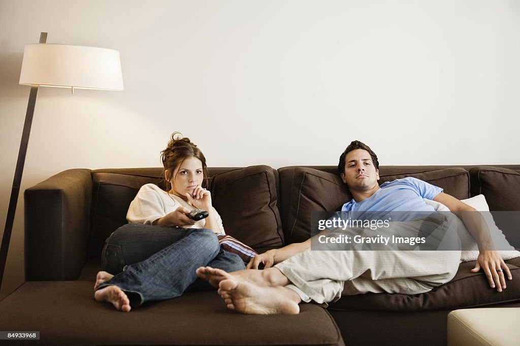 Young couple on sofa watching television.