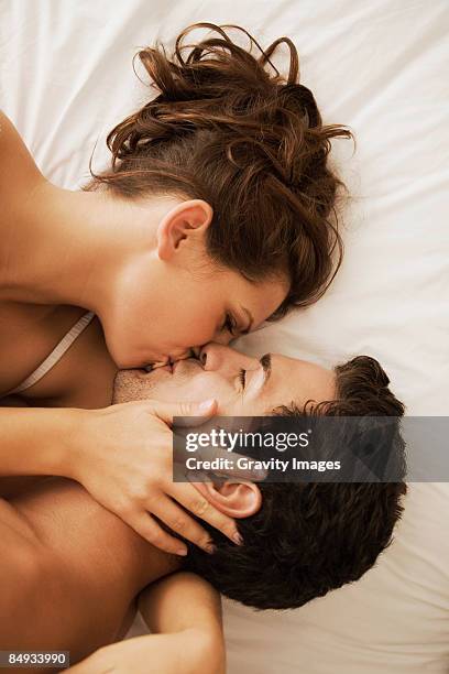 close-up of young couple in bed kissing. - beijando - fotografias e filmes do acervo