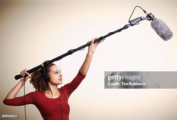 young woman using boom microphone and headphones  - equipe cinematografica foto e immagini stock