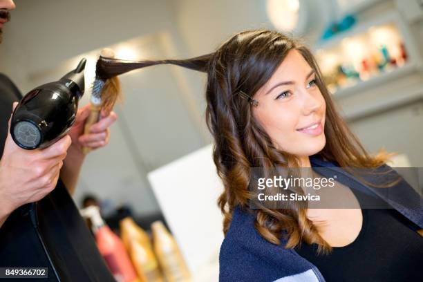 jovem mulher sorridente fazendo novo penteado no salão de cabeleireiro - secador de cabelo - fotografias e filmes do acervo